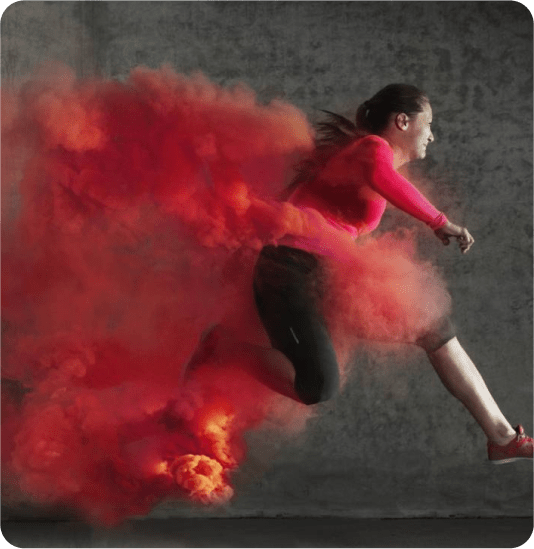 A woman runner speeding or jumping through a red cloud
